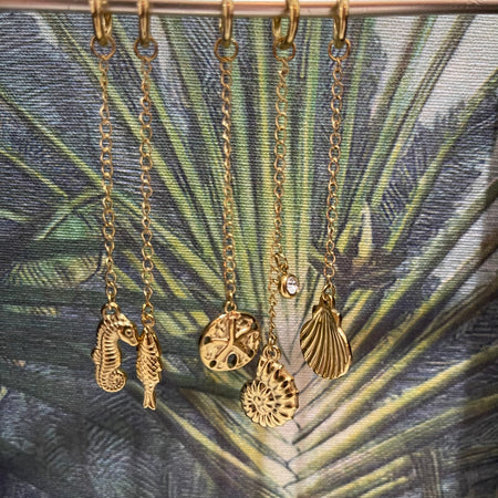 Gold coastal bikini charms including seahorse, sand dollar, shell, scallop shell and fish designs arranged together, made from PVD gold plated stainless steel.