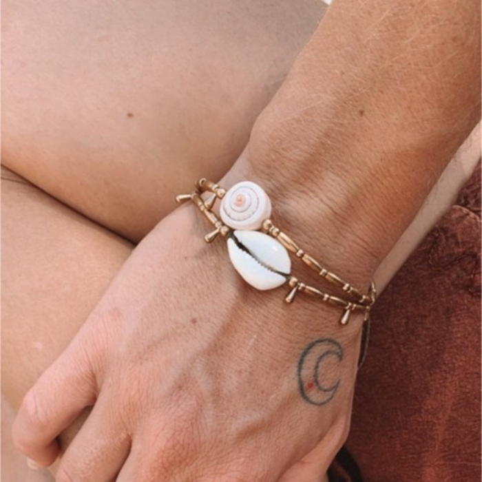 Brass droplet cowrie anklet styled on ankle showing versatile bohemian beach jewelry