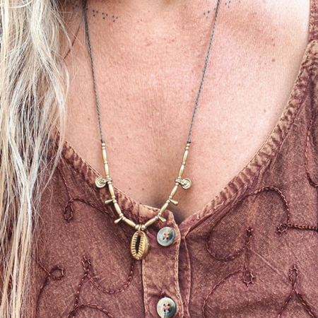Cowrie brass beaded necklace styled on model showing versatile bohemian coastal jewelry