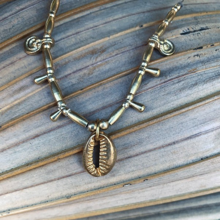 Close up detail of adjustable cowrie shell necklace showing brass beads and sliding knot closure