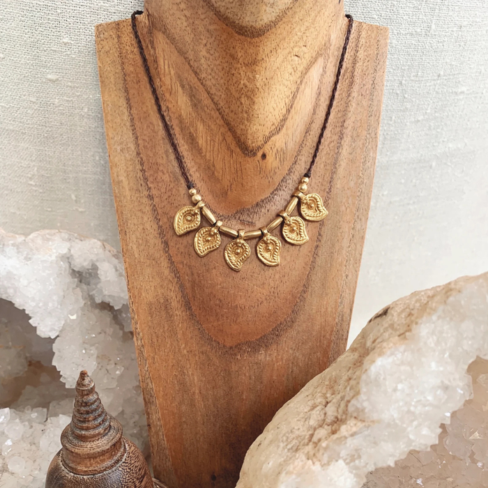 Handmade brass charm necklace with adjustable cord worn as choker