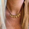 Handmade brass charm necklace with adjustable cord worn as choker