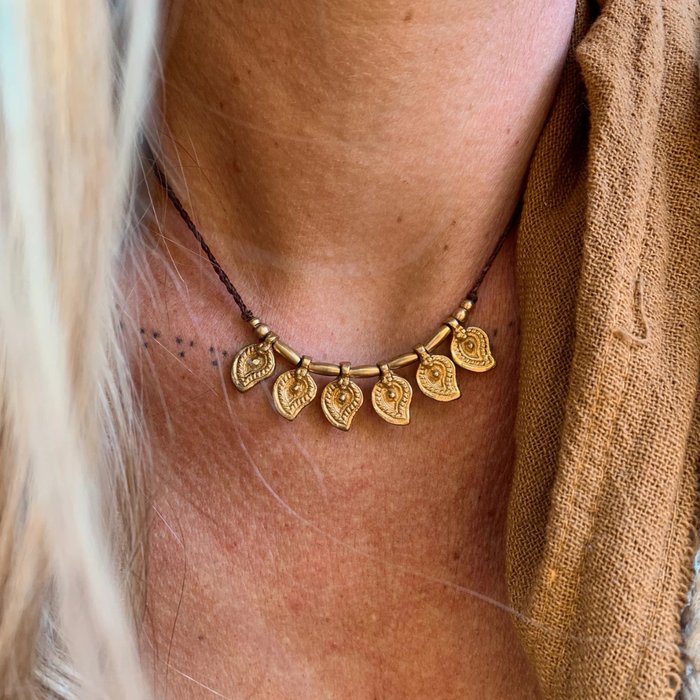 Handmade brass charm necklace with adjustable cord worn as choker