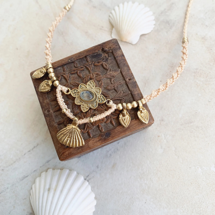 Quartz charm necklace laid flat showing adjustable macrame cord and brass details