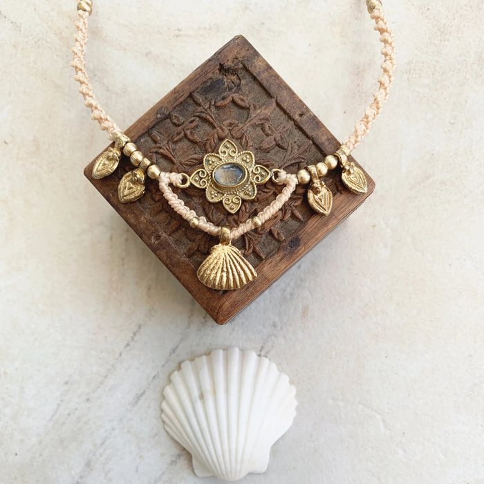 Close-up of natural quartz gemstone with brass beads on macrame necklace