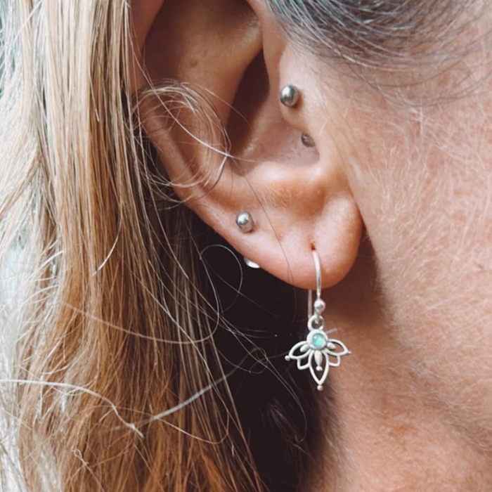 Labradorite lotus earrings with iridescent blue-green stones styled on model